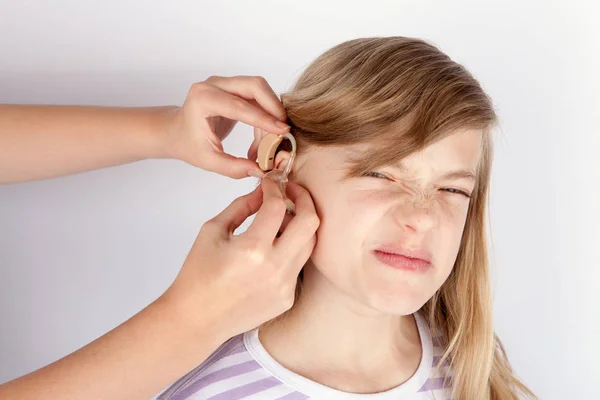 Jovem paciente menina não muito feliz, enquanto as mãos inserir uma audição — Fotografia de Stock