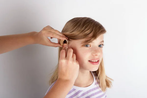 Close up of a Doctor's hands fitting a hearing aid for a young g — Stock Photo, Image