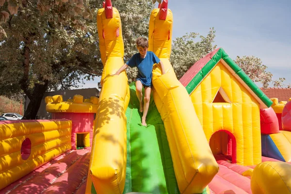 Jongen speelt in een opblaasbare speelgoed huis in een park — Stockfoto