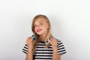 Beautiful young girl playing with two fidget spinners clipart