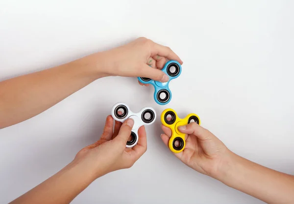 Three hands showing fidget spinners in different colors — Stock Photo, Image