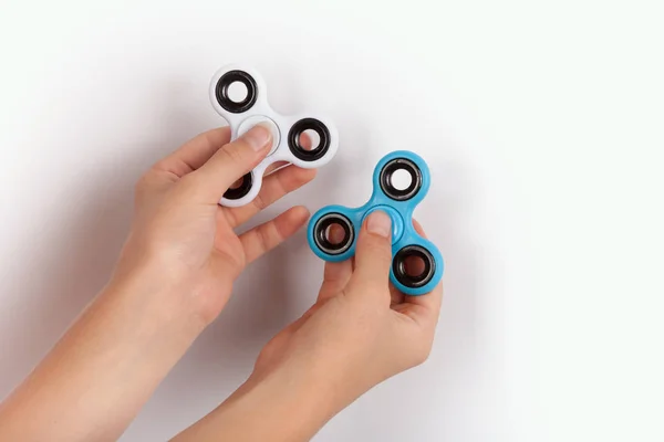 Hands with a white and a blue fidget spinners — Stock Photo, Image