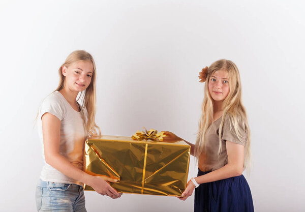 Две красивые девочки-подростки с большой коробкой подарков
