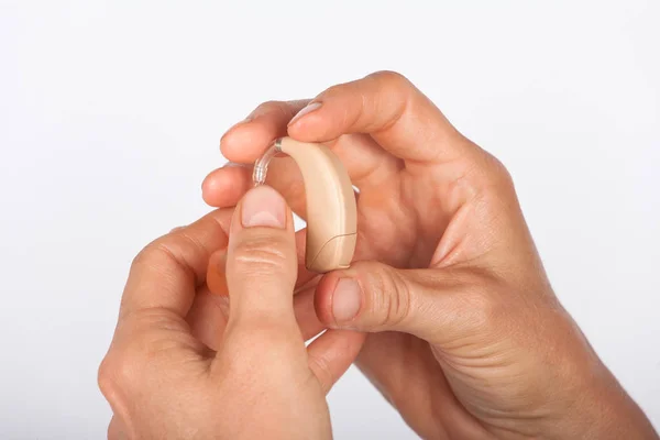 Close up of a womans hands holding a hearing aid — Stock Photo, Image