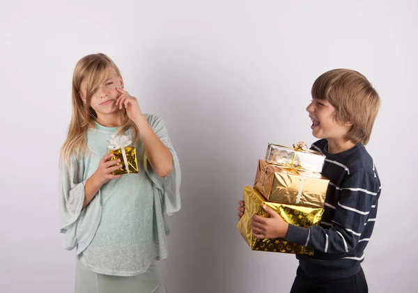 Menina triste com um pequeno presente e um menino com um monte de presentes risos — Fotografia de Stock