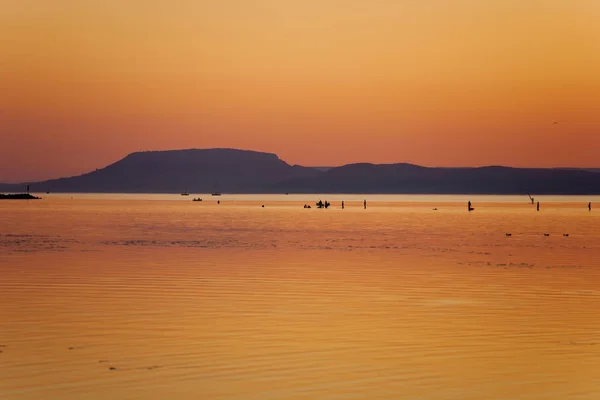 Západ slunce ve zlatých barvách nad jezero Balaton s koupajících silhouet — Stock fotografie