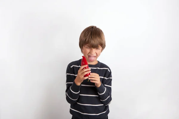 Young boy holding a paprika expressing disgust and stretches out — Stock Photo, Image