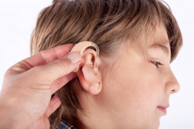 El bir genç çocuğun kulağına işitme cihazı ekleme