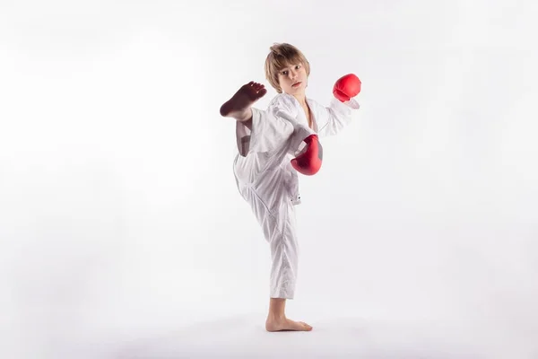 Kleiner Junge mit Kimono und roten Boxhandschuhen, die Übungen zeigen — Stockfoto