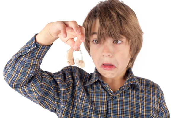 Grijnzende jongen tonen van een gehoorapparaat. Geïsoleerd op een witte pagina — Stockfoto