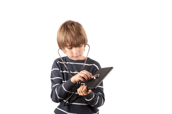 Junge inspiziert sein Tablet-Gerät mit Stethoskop. isoliert auf w — Stockfoto