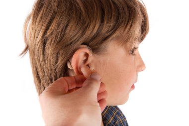 El bir genç çocuğun kulağına işitme cihazı ekleme. Beyaz arka plan üzerinde izole.