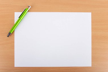 Ahşap bir masa üzerinde bir kalem ile beyaz boş kağıt levha