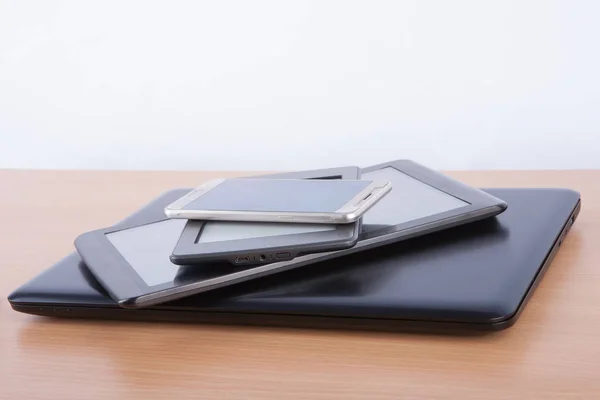 Stack of electronic gadgets on a table - notebook, tablet, ebook — Stock Photo, Image