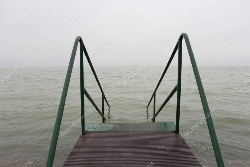 Bad weather over a lake with a gray and characterless sky and wi