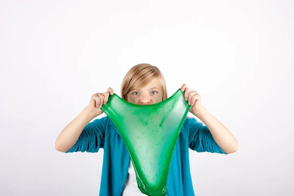 滑稽的女孩拿着绿色的粘液看起来像黏糊糊的在她的前面 f — 图库照片