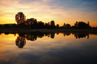 Bir sakin göl su yüzey günbatımında yansıtan ağaçlar