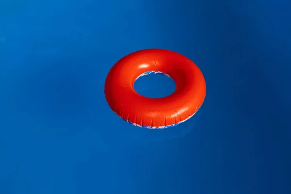 수영용 푸른 물 위에 떠 있는 붉은 부풀링 스톡 사진
