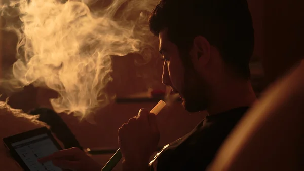 Mężczyzna pali fajki i korzysta z tabletu — Zdjęcie stockowe