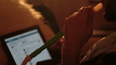 adam bir nargile içiyor ve tablet kullanır