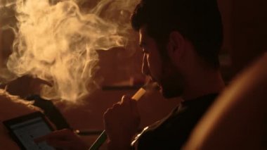 adam bir nargile içiyor ve tablet kullanır