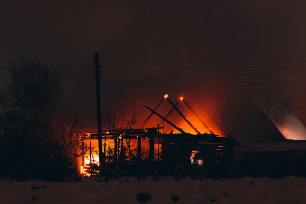 Fuego en una casa de madera por la noche — Foto de Stock