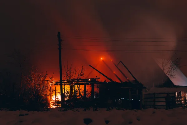Fuego en una casa de madera por la noche — Foto de Stock