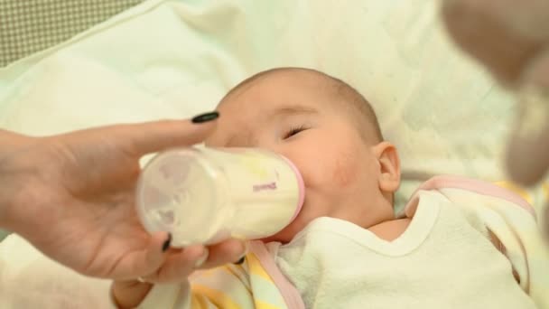 Маленький новорожденный ребенок ест молоко из бутылки — стоковое видео