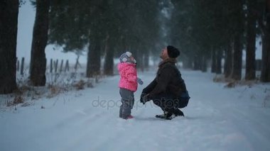 Baba küçük kızı parkta kışın yağan kar zevk ile