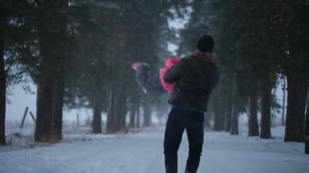 Padre entrega en sus brazos a su pequeña hija en el parque en invierno — Vídeos de Stock