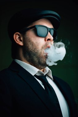 Güneş gözlüğü ve deri şapkası moda erkekte exhales beyaz duman