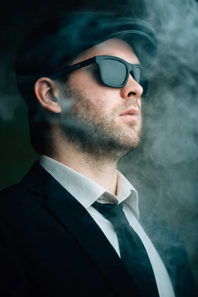 Muž na sobě sluneční brýle a koženou čepici v kouři — Stock fotografie