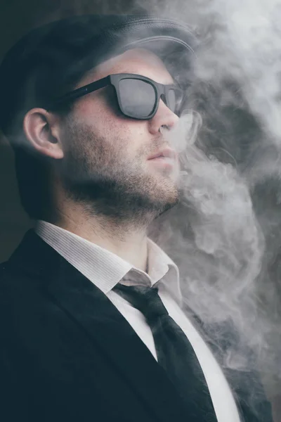Мужчина в солнцезащитных очках и кожаной кепке в дыму — стоковое фото