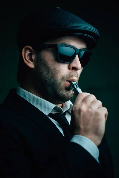 Modischer Mann mit Sonnenbrille und Ledermütze raucht — Stockfoto
