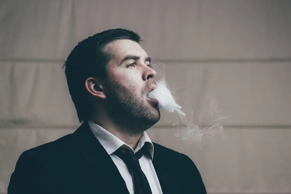 Podnikatel vydechuje cigaretového kouře — Stock fotografie