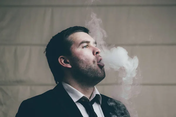 Podnikatel vydechuje cigaretového kouře — Stock fotografie