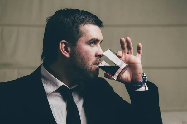 Бизнесмен пьет стакан виски — стоковое фото