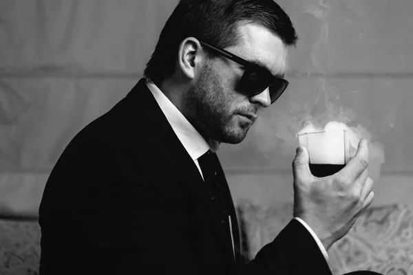 Человек в солнцезащитных очках смотрит на парящий напиток стакан — стоковое фото
