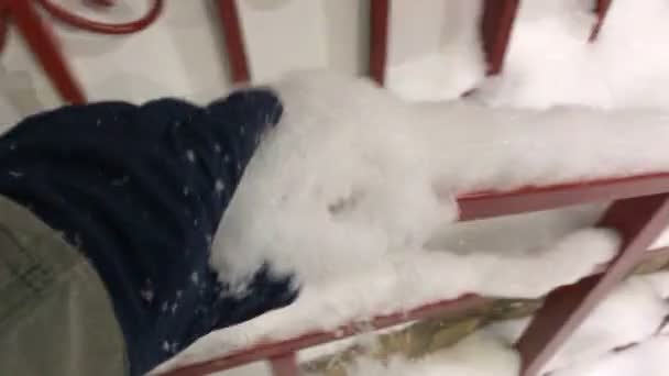Hand in de handschoen wegspelen van de sneeuw van de reling — Stockvideo