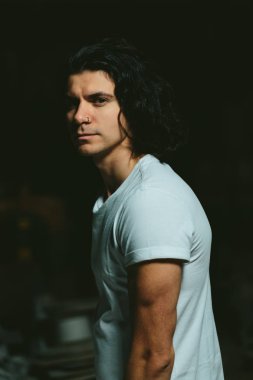 karanlık bir arka plan üzerinde uzun saçlı acımasız adam