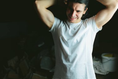 Güzel uzun saçlı esmer adam elleri arkasında beyaz t-shirt kafasında