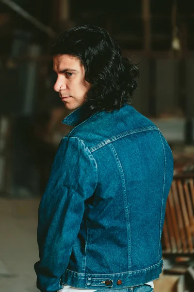 Pohledný muž s dlouhými vlasy brunetka v džínové bundě — Stock fotografie