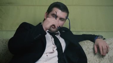 kanepe yakın çekim oturan işadamı. İşadamı güneş gözlüğü takıyor