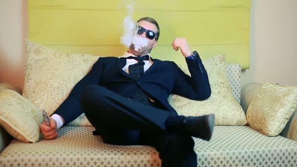 Elegantní mladý podnikatel kouří elektronické cigarety na pohovce — Stock video