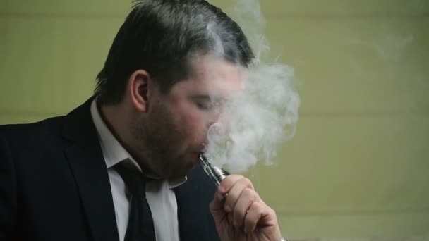 Jovem empresário elegante fuma cigarro eletrônico close-up em um sofá — Vídeo de Stock