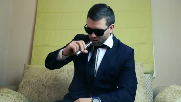 Elegantní mladý podnikatel kouří elektronické cigarety na pohovce — Stock video