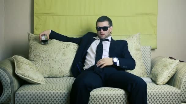 Hombre de negocios con un vaso de whisky en el sofá — Vídeos de Stock