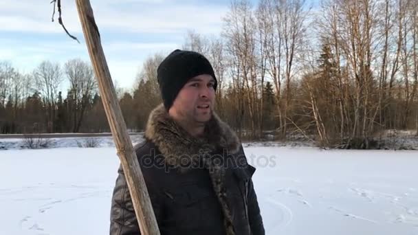 En man med en torr pinne i händerna på vintern i slow motion — Stockvideo