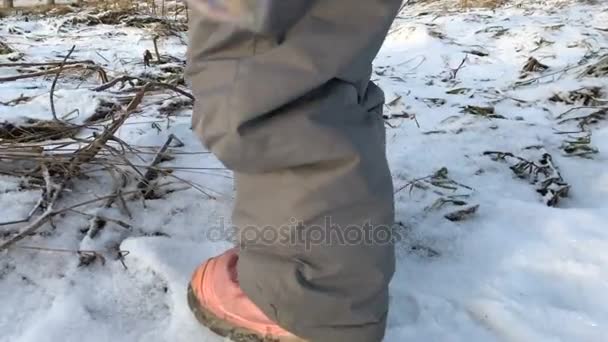 Un petit enfant marche au ralenti sur une surface enneigée du champ — Video
