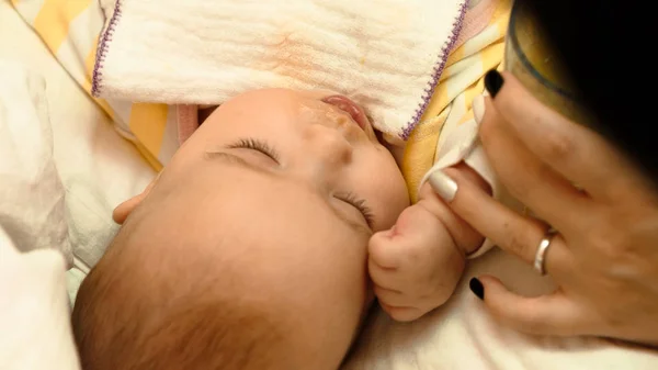 Mãe alimenta seu pequeno filho purê de bebê com colher — Fotografia de Stock